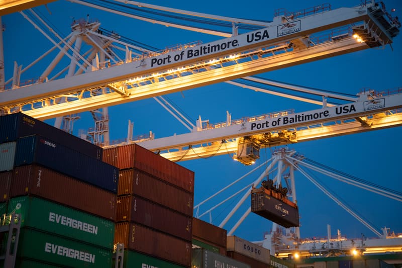 Gantry cranes at the Port of Baltimore at dusk, a container in the air